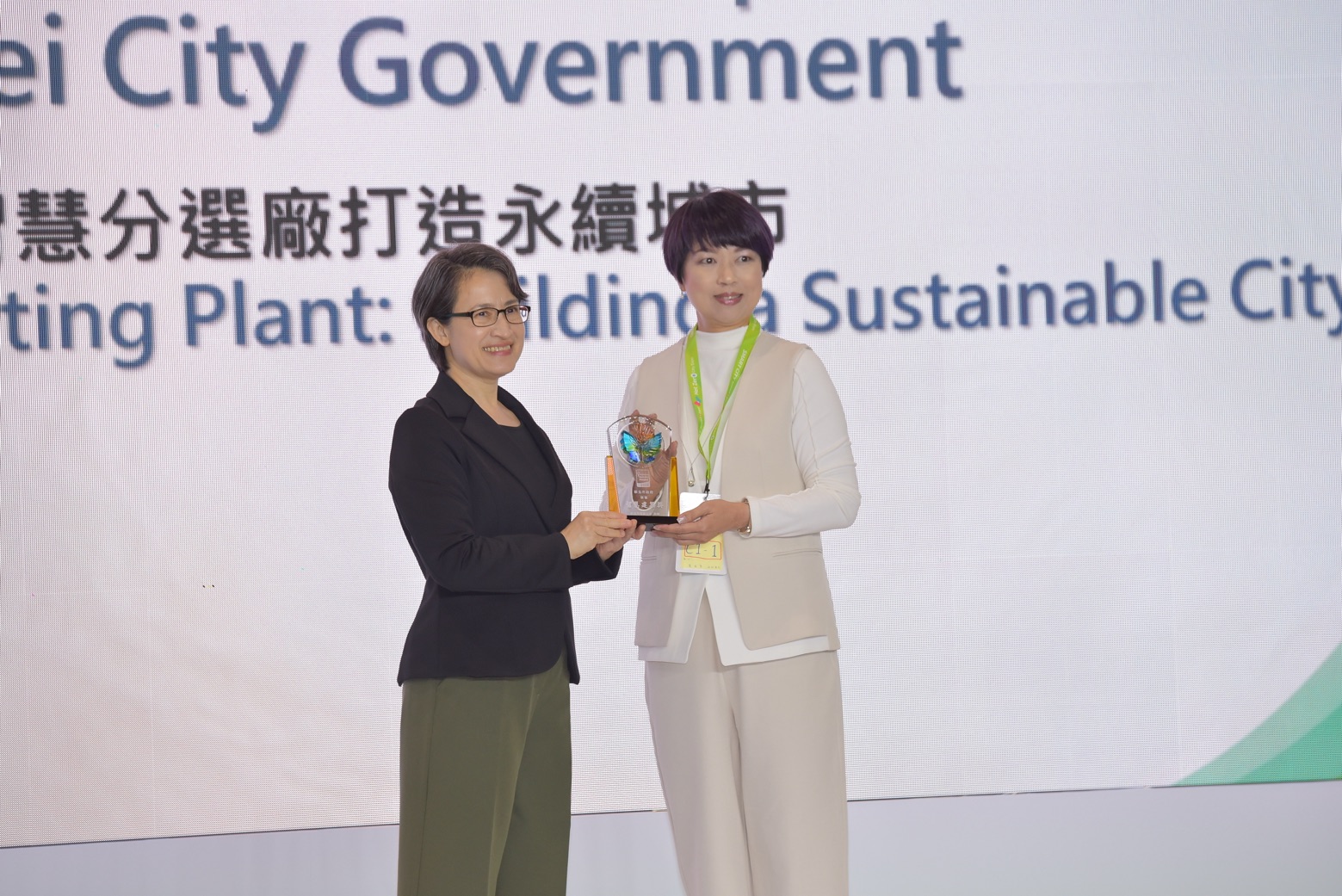 《圖說》新北市政府「建築執照AI輔助審查」及「AI智慧分選廠打造永續城市」，榮獲智慧城市創新應用獎，副總統蕭美琴（左）頒發表揚，新北市政府副秘書長龔雅雯（右）代表市府團隊領獎。〈工務局提供〉