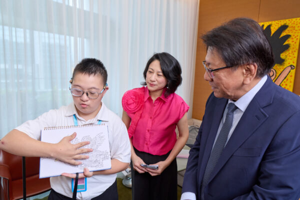 總統府秘書長潘孟安（右）於開幕典禮前參觀兒少藝術展間，在 Arteen Taipei 創辦人暨策展人王貞懿（中）陪同下，聆聽公益展間參展生分享創作與手稿，近距離了解孩子的藝術世界。圖/墨兒藝術提供